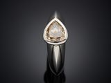 a white gold ring with a pear shaped diamond on a black surface