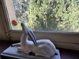 une statue représentant un oiseau perché sur un plateau devant une fenêtre
