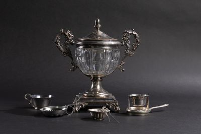 une tasse en argent posée sur une table, à côté d'un service à thé