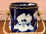 a blue and white vase with a handle on a wooden table