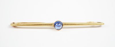 a close up of a gold tie bar with a blue stone