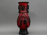 un vase rouge orné de motifs noirs, posé sur une table