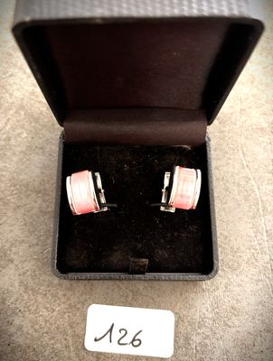une paire de boutons de manchette roses et blancs dans un coffret noir
