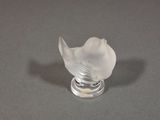un oiseau en verre posé sur un socle en argent