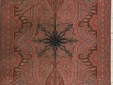 un vieux tapis rouge et noir sur lequel se trouve une araignée