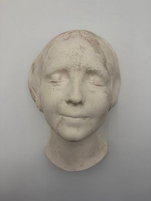 plaster sculpture of a woman ' s face on a white wall