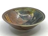 un bol marron et vert posé sur une surface blanche
