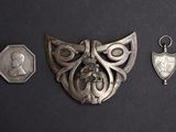 three pieces of silver metal on a black surface with a coin and a medal