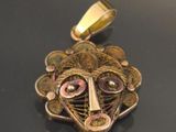 a close up of a gold pendant with a face on it