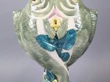 a green and white owl figurine sitting on a wooden stand