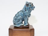 statue of a dog sitting on a wooden base on a white background