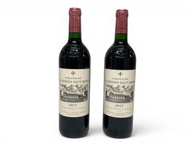 two bottles of red wine sitting next to each other on a white surface