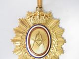 gold medal with a masonic symbol on it hanging from a white wall