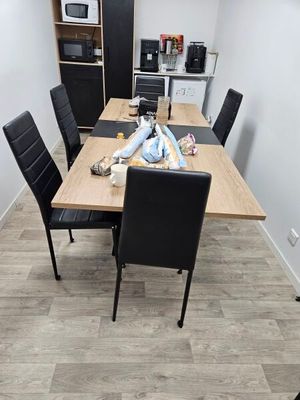 a wooden table with black chairs in a small room