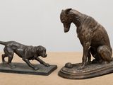 deux statues en bronze représentant un chien et un chat, posées sur une table