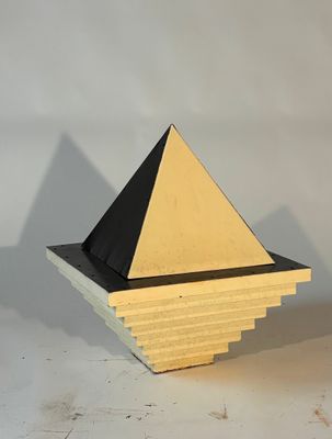 yellow and black pyramid shaped object on a white surface