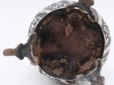 an antique silver teapot with a brown glass lid on a white surface