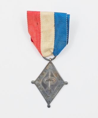 une vieille médaille sur fond blanc, accompagnée d'un ruban rouge, blanc et bleu