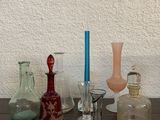 de nombreux vases en verre de différentes formes posés sur une table avec une bougie