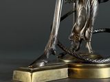 an antique bronze statue of a woman holding a snake on a base