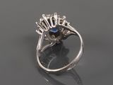 a close up of a diamond and sapphire ring on a reflective surface