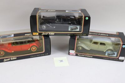 trois modèles réduits de voitures dans leurs boîtes, posés sur une surface blanche