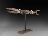 une sculpture en bois représentant un poisson, posée sur un socle en métal