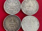trois pièces d'argent, dont l'une a la même taille que les autres, se trouvent sur une surface rouge