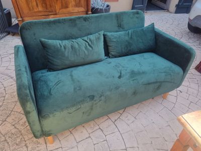 a green couch with two pillows on it in a living room
