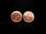 une paire de boucles d'oreilles en or sur une surface noire