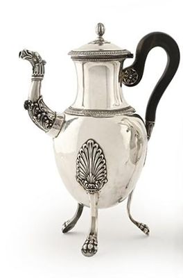 une théière en argent avec une anse noire, posée sur un socle