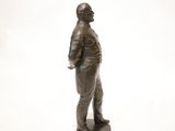 bronze statue of a man standing on a base with his hands in his pockets