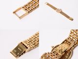 three pieces of gold bracelets and a watch on a white surface