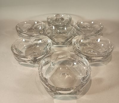 several clear glass bowls are arranged in a circle on a white surface