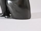 a black cat statue sitting on a white surface