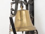 une cloche accrochée au mur, entourée d'une chaîne