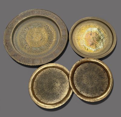 trois plaques en laiton et un bol posés sur une surface grise