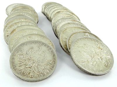 des pièces de monnaie posées sur une surface blanche, dont l'une se trouve au premier plan