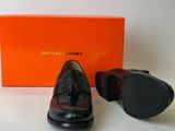 black leather shoes with tassels and a box on a white surface