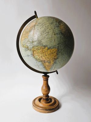 un vieux globe terrestre posé sur un socle en bois, sur fond blanc