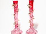 deux vases roses ornés de fleurs, posés sur une surface blanche