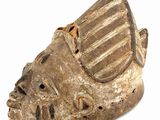 a close up of a wooden mask on a white surface