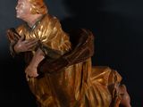 statue of a woman sitting in a chair with her hands on her knees