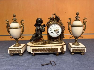 trois statues et une horloge posées sur une table