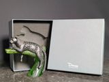 une figurine représentant un chat assis sur une branche, dans une boîte