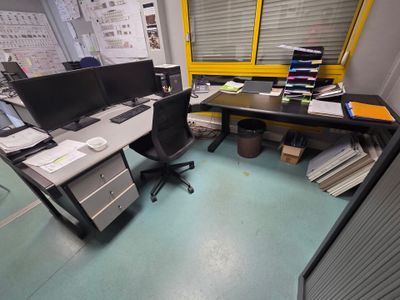 un bureau avec deux écrans d'ordinateur et une chaise dans un coin