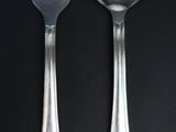 two spoons and a fork on a black table
