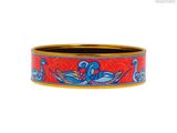 un gros plan sur un bracelet rouge et bleu orné d'un oiseau