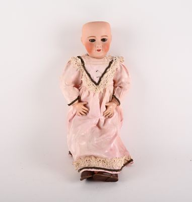 Une poupée à l'ancienne est assise sur une surface blanche