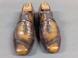 pair of brown leather shoes with tassels on them on a gray surface